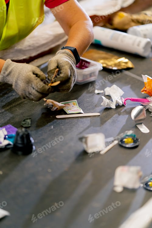 Preview: Close-up hands in work gloves sorting garbage into categories on a special line at factory