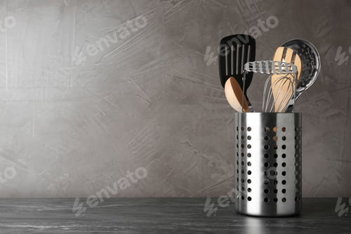 Preview: Holder with kitchen utensils on grey table against grey stone background. Space for text