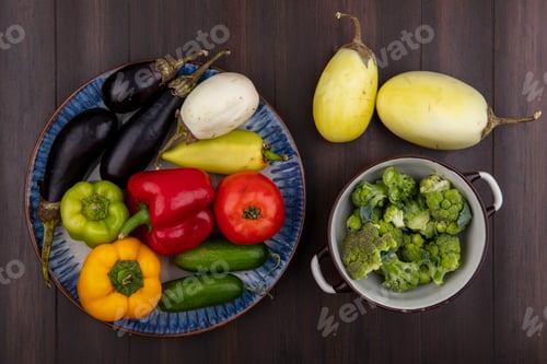 Preview: top view colored bell peppers with cucumbers and tomatoes eggplant on a plate and broccoli in a bowl
