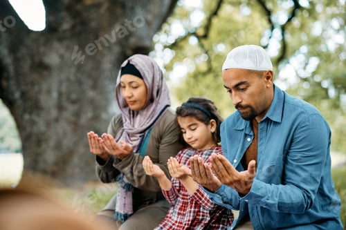 Preview: Muslim man and his family praying while spending a day in nature.
