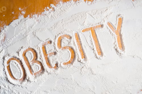 Preview: Obesity. Handwritten word on a wooden table.