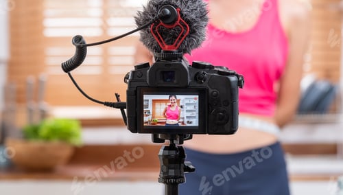 Preview: Young Asian blogger holding measuring tape around her wais while recording video