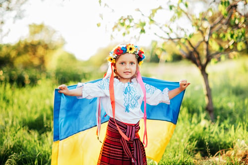 Preview: Ukrainian child girl in embroidered shirt vyshyvanka with yellow and blue flag of Ukraine in field