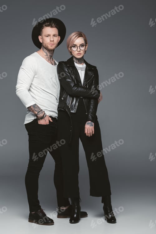 Preview: fashionable tattooed couple posing together, isolated on grey