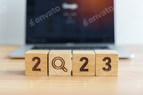 Preview: 2023 block with magnifying glass icon against laptop background.