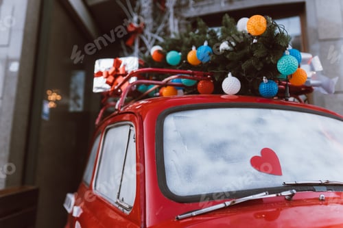 Preview: Red retro car with a Christmas tree fir tied to the roof