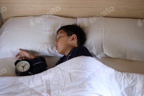 Preview: Asian cute boy sleeping in bed with alarm clock