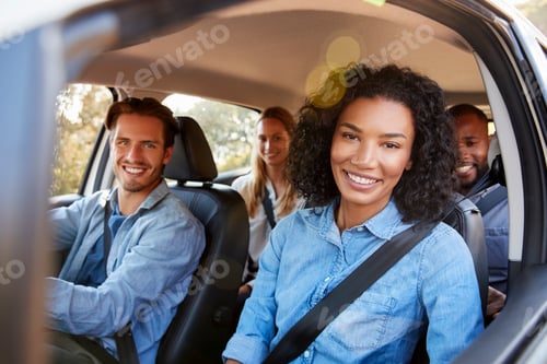 Preview: Four adult friends in a car on a road trip smiling to camera