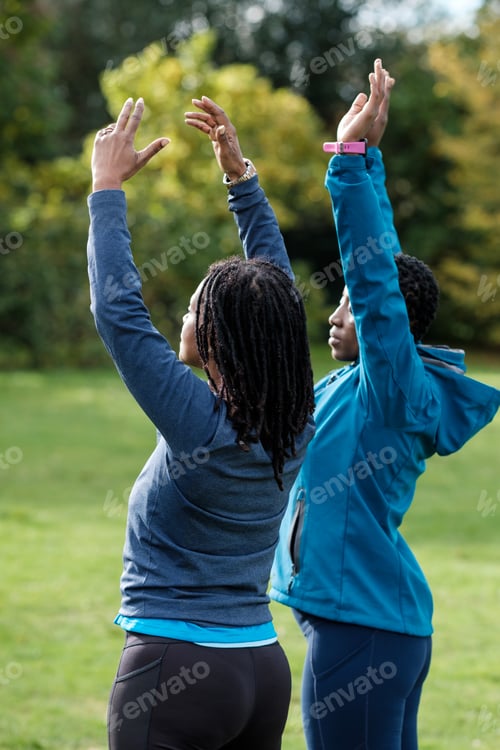 Preview: Two mature women meditating and stretching outdoors.
