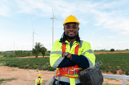 Preview: Portrait of smart engineer with protective helmet at electrical turbines field