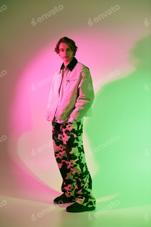 Preview: Fashionable young man showcases modern style under vibrant spotlight