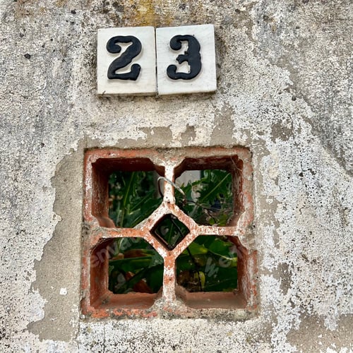 Preview: Closeup of a window in a concrete wall with a numbers 23 on top