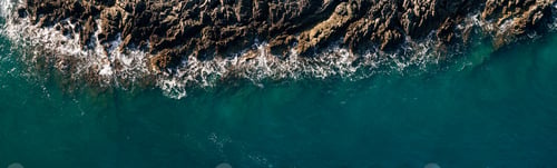 Preview: The ocean's wave hitting rocks. Blue water background. Aerial view. The natural landscape. Wallpaper