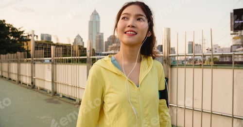 Preview: Young Asia athlete lady exercises using smartphone for listen to music while running in urban.