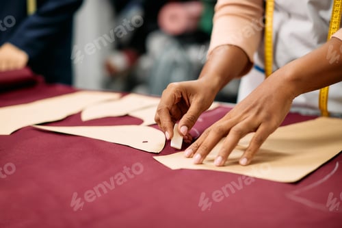 Preview: Close-up of tailor marking pattern with chalk on fabric while working at clothing studio.