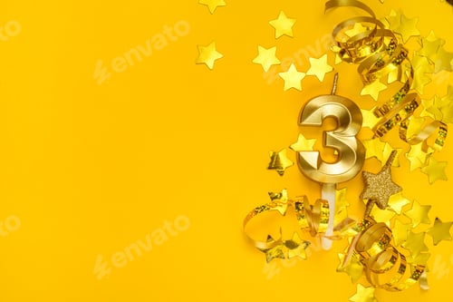 Preview: Gold candle in shape of number three on yellow background surrounded by stars confetti and streamers