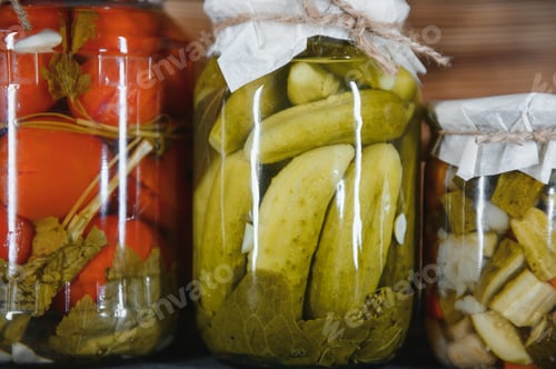 Preview: Canned cucumbers and tomatoes with craft lids on a wooden background.