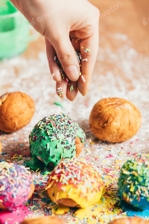 Preview: Woman sprinkling sugar strands on doughnuts