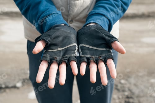 Preview: Man showing hands in torn sports gloves from training. Used sportswear, close-up