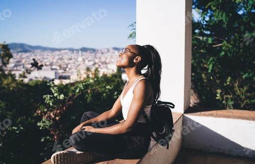 Preview: carefree female student with touristic backpack resting at lookout place