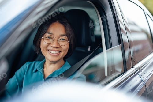 Preview: Portrait of a happy Asian businesswoman driving to work.