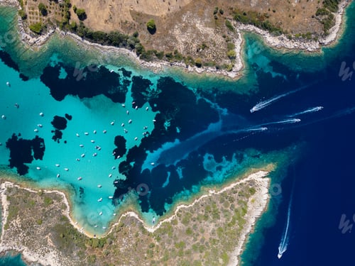 Preview: Aerial view of a turquoise lagoon with numerous boats floating on clear water, surrounded by dark
