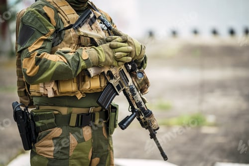 Preview: Shallow focus of a special force soldier holding his gun outdoors with a blurry background