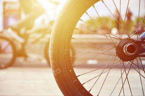 Preview: A BMX bike wheel against the backdrop of a blurred street with cycling riders