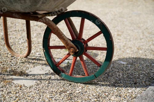 Vista previa: Primer plano de una rueda roja y verde de una carretilla parada afuera en la granja