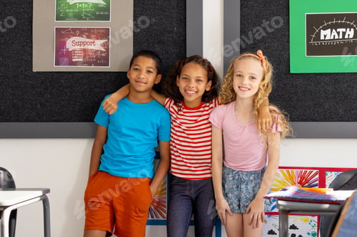 Preview: In school, three young students posing together in the classroom, two biracial and one Caucasian