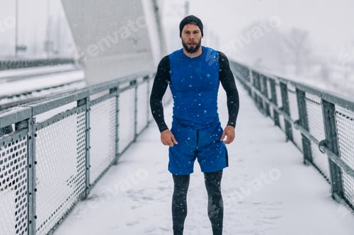 Preview: Man stretching before training on bridge during a winter snow day.