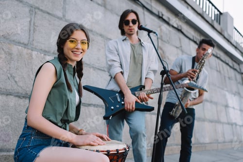 Preview: Young hipster buskers with musical instruments playing at city street