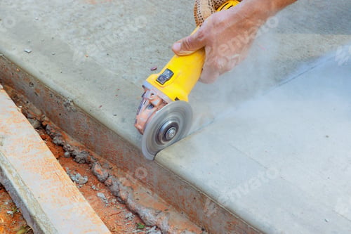 Preview: An employee of construction industry cuts concrete foundation after it has been poured using a