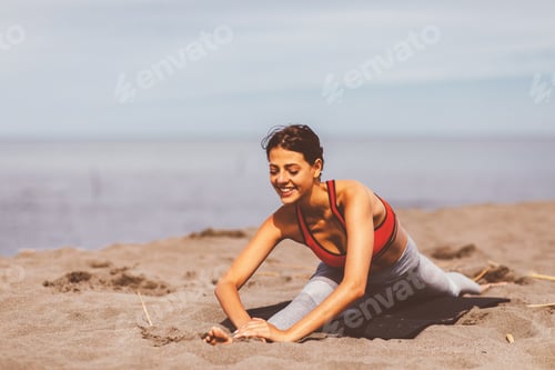Preview: Young woman stretching on the beach