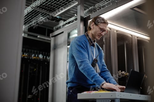 Preview: Middle Aged Caucasian Man Working on Laptop in Data Center Server Room