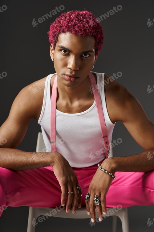 Preview: good looking man in stylish attire with suspenders and accessories posing on chair, fashion concept
