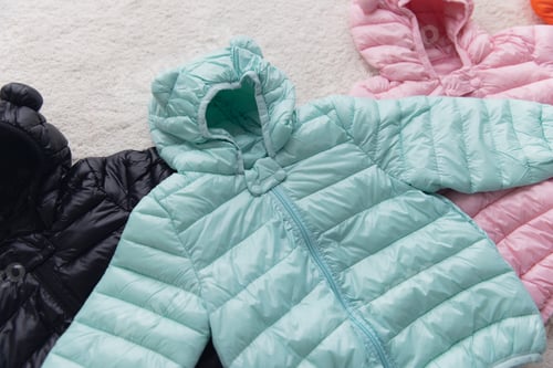 Preview: Colorful children's down jackets on white fur carpet