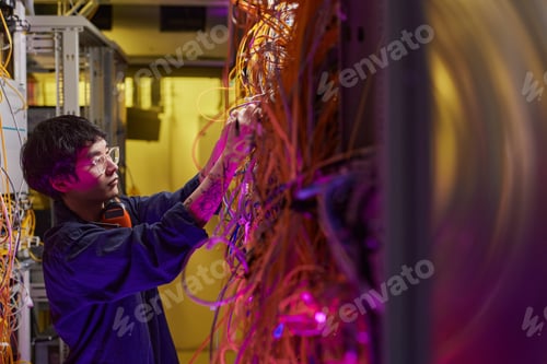 Preview: Young Man Connecting Cables in Server Room