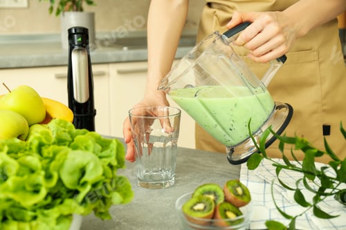 Preview: Woman pour smoothie from blender jug into glass