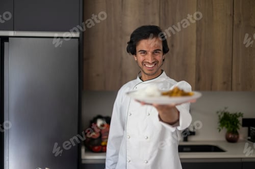 Preview: Smiling chef in white uniform presenting a plate of rice and curry in a modern kitchen.