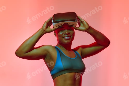 Preview: African american woman streamer playing video game using virtual reality glasses at gaming room