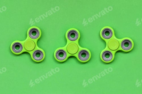 Preview: Many green fidget spinners lies on texture background of fashion pastel green color