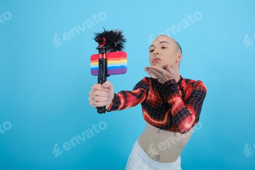 Preview: Non-binary person sending a kiss to the mobile phone camera while streaming or recording vlog.