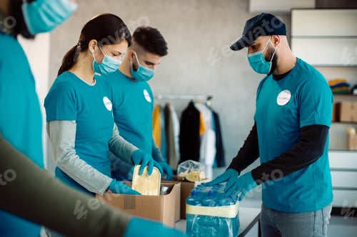 Preview: Group of volunteers packing donation boxes with food and drinks for charity.