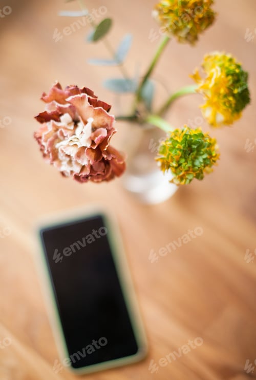 Preview: A mobile phone on the table in a cafe with flowers in the vase, using technology, smartphone