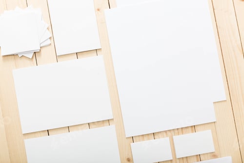 Preview: Blank sheets of white paper organized on a wooden table ready for creative projects and artwork