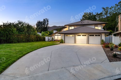 Preview: A two-story house with a three-car garage, large driveway, and well-maintained lawn at dusk