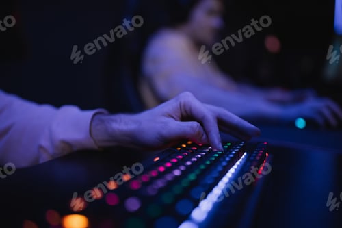 Preview: Cropped view of gamer using keyboard with colorful lighting in gaming club
