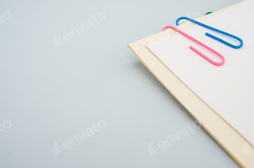 Preview: Closeup shot of a blank paper with colorful paper clips on a light green background