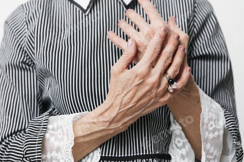 Preview: Mature woman with wrinkled hands in a contemplative gesture against a plain white background